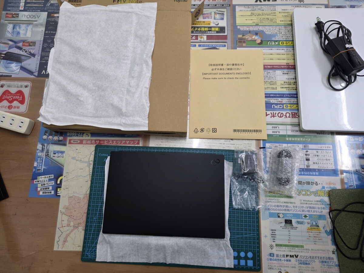 開梱後、緩衝材に包まれたパソコン本体と、取扱説明書の入った封筒、ACアダプター一式がテーブルに並んでいる様子