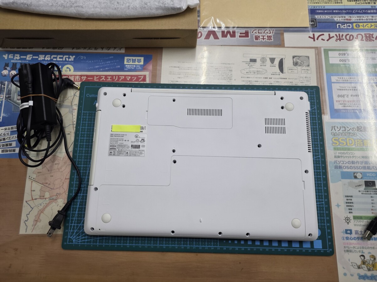 廃棄処分前のFUJITSU LIFEBOOK AH50/C2の底面。白いボディにモデルシールが貼られており、カッティングマットの上に置かれている